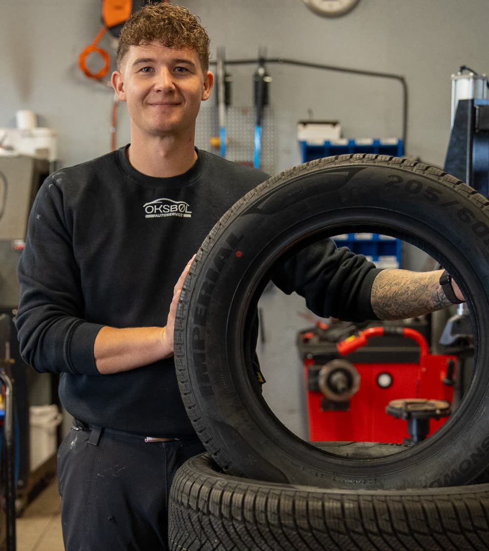 Mekaniker hos Oksbøl Autoservice med et sæt vinterdæk